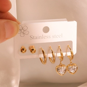 Three pairs of gold stainless steel earrings with heart zircon pendants on a white card