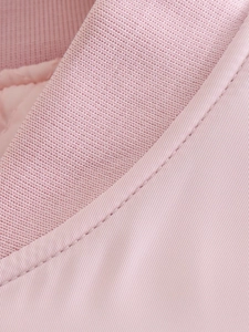 Macro detail of pink bomber jacket showing knitted rib collar and smooth woven fabric