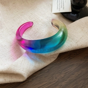 Irregular chunky acrylic bangle with vibrant rainbow gradient finish on linen