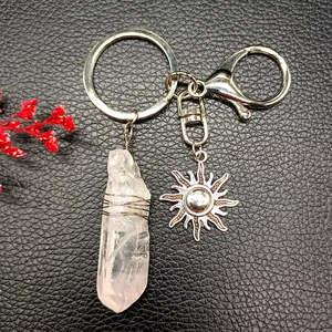 Detail of natural crystal sun keychain with silver wire-wrapped stone on black leather