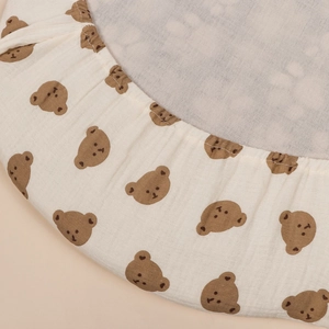 Detailed close-up of baby cradle cover with bear print and elastic edge for fit