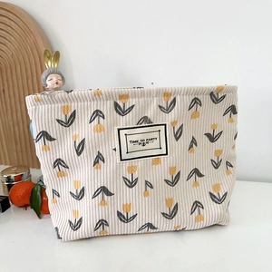 Close-up of corduroy makeup bag featuring yellow tulips and Time to Party woven label