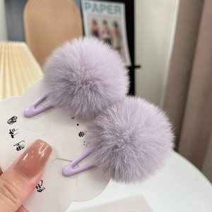 Close-up of lavender faux fur ball hair clips on cloud-shaped card with metal duckbill clips