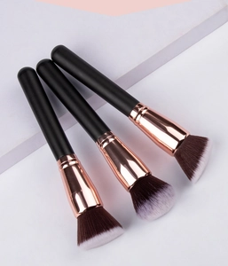 Detailed view of three professional makeup brushes with rose gold ferrules and dual-tone bristles