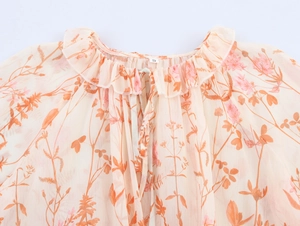 Detail des Rüschenausschnitts am beigen Blumen-Chiffonkleid mit feinem orangefarbenem Muster