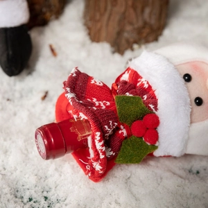 Knitted Christmas wine bottle cover in red with plush trim on snowy background