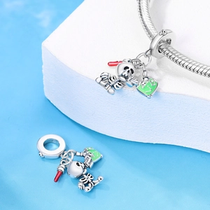 Detailed view of silver skull and heart charm with red and green enamel on a bracelet