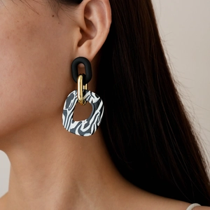 Close-up of geometric acrylic earrings with marble pattern and matte black oval link