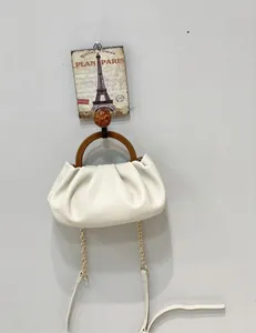 Close-up of a white pleated dumpling bag with wood-texture handles and gold chain strap