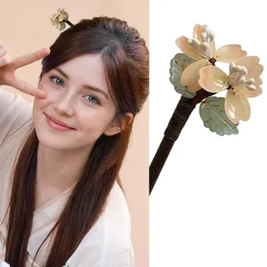 Détail d'une pince à cheveux fleurie abricot avec feuilles vert clair et clip à ressort