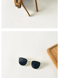 Detail of foldable square frame kids sunglasses in ginger and white on wood tray