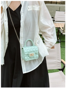 Detail of mint green quilted jelly bag with metal chain strap in outdoor setting