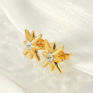 French style 18K gold starburst stud earrings with clear zircon on silk background
