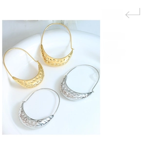 Detailed view of large hammered texture boat-shaped earrings in gold and silver plating