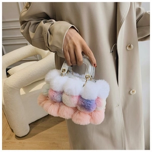 Detail of colorful plush handbag with pastel faux fur pom-poms and white leather handle