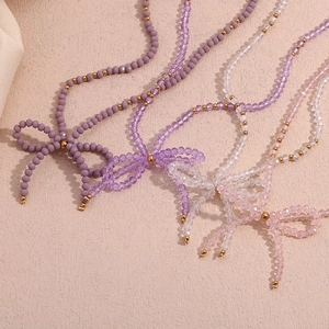 Artistic overhead view of purple crystal beaded necklaces arranged in a bow shape
