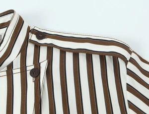 Dettaglio camicia a righe con bottoni marroni, spalline e cuciture di precisione