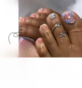 Détail de faux ongles de pieds French rose et bleu avec motif papillon et strass brillants
