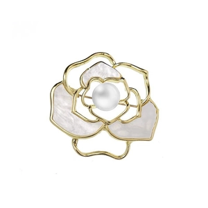 Elegant gold flower brooch with white shell petals and central pearl on white background