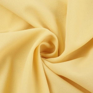 Dettaglio ravvicinato del tessuto chiffon giallo con texture plissettata morbida e drappeggi