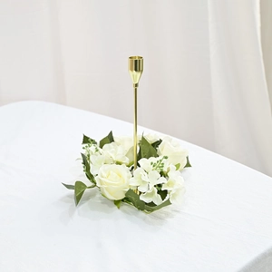 Detailed view of elegant gold metal candle holder with white rose wreath on table