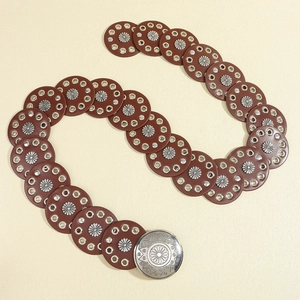 Close-up of brown vintage leather belt with silver floral metal studs and round buckle