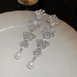 Detail of silver drop earrings with sparkling rhinestones and white pearls on a plate