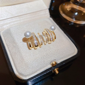 Macro shot of gold layered claw earrings with white pearls and sparkling zircons