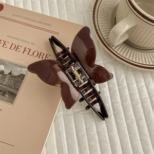Brown acetate butterfly hair claw clip with metal spring on a vintage French book