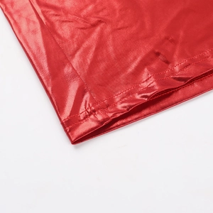 Détail du tissu rouge brillant montrant la couture à double aiguille sur l'ourlet