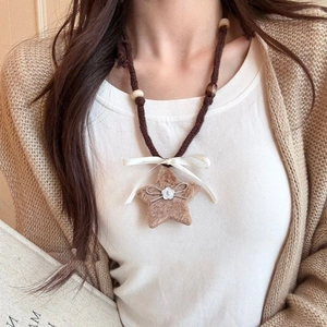 Detailed view of handmade plush star pendant with bow and wooden beads on woven cord