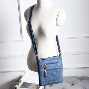 Blue denim crossbody bag featuring multiple zippers and side view on mannequin