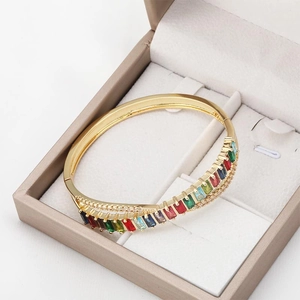 18K vergoldetes geometrisches X-Armband mit bunten Zirkonsteinen in einer beigen Geschenkbox