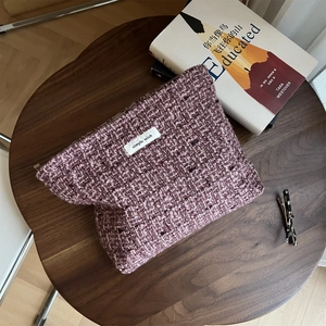Close-up of pink tweed makeup bag with 'Simple Wish' label on a rustic wooden table