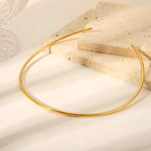 Poliertes goldenes Edelstahl-Halsband auf einer minimalistischen Steinplatte
