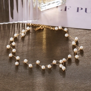 Close-up of heart pearl necklace with golden metal clasp on a textured dark background