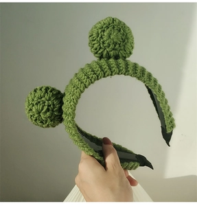 Close-up of green crochet knit frog headband showing wool texture and 3D eye detail