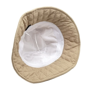 Detail view of beige quilted bucket hat showing white lining and adjustable drawstrings