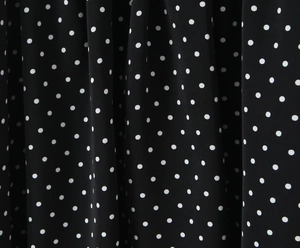 Détail rapproché d'un tissu noir léger avec un motif classique à pois blancs