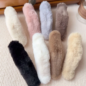 Macro detail of eight colorful plush faux fur hair clips on a soft beige striped fabric