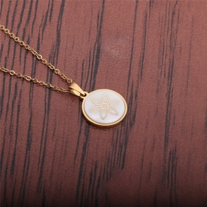 Titanium steel necklace with gold flower pendant on white shell over wood background