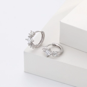 Detail view of silver S925 earrings with square zircon on white geometric stands