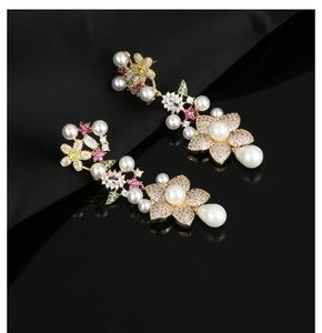 Macro shot of gold flower earrings with colorful zircon and pearls on black silk