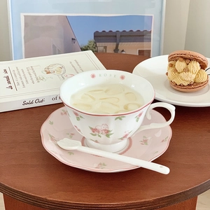 Detail of pink rabbit and rose ceramic coffee cup with gold-rimmed saucer and spoon