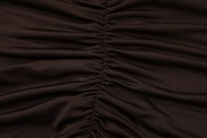 Detailed macro view of deep brown knitted fabric with ruched texture and elastic seams
