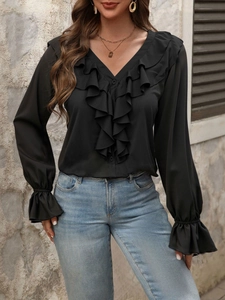 Elegante blusa negra con cuello en V y volantes de manga larga con vaqueros
