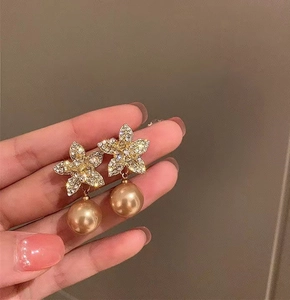 Detailed macro view of gold star stud earrings featuring rhinestones and hanging pearls