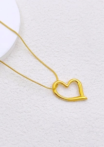 Detail shot of a gold hollow heart pendant on a delicate snake chain necklace