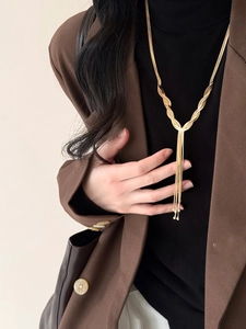Detail of layered gold fringe necklace with woven snake chains on black garment