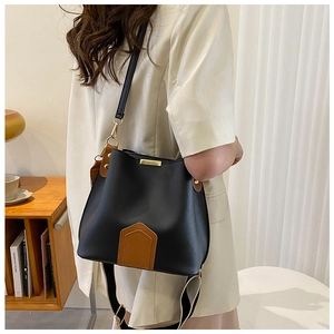Détail du sac seau bicolore en cuir avec base marron et garniture métallique dorée